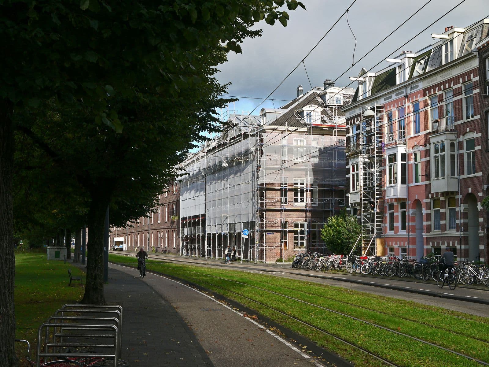 Straat met bakstenen woningen in de steigers, bomen en fietsers
